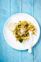 Fettuccine Pasta with sauce. Hot dish with Parmesan cheese, decorated with green parsley on a blue background.Copy space for Text.selective focus.