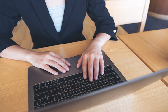 Closeup image of a business woman working and typing on laptop keyboard on the table
