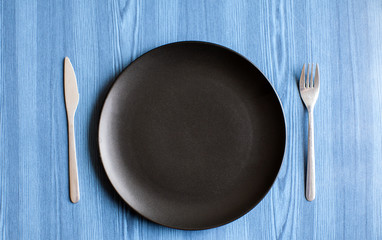 Black Dinner Plate with knife and fork on a table