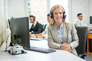 Smiling cute young woman customer support call operator in office