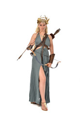 full length portrait of pretty blonde lady wearing fantasy toga gown,  and holding a bow and arrow. standing pose on white background.