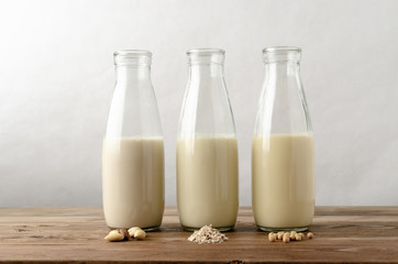 Row of Dairy Free Milk Alternatives with Ingredients on Wood Planked Table