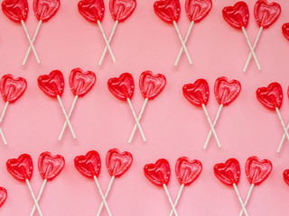 Two red heart lollipop pattern on pink background