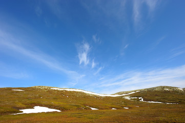 Fototapeta premium Karge Landschaft vor blauem Himmel mit Wolken