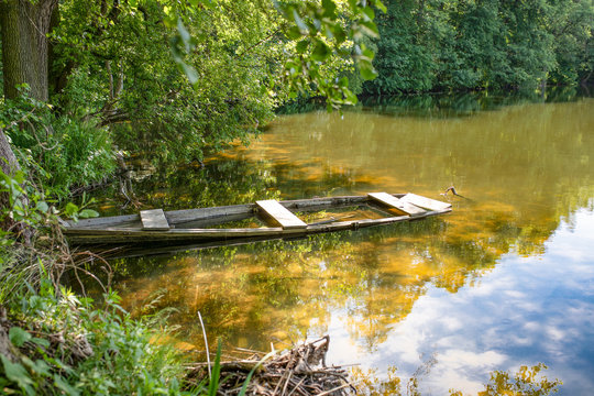 Masurian lake and a fishing boot. Colorful leaves, blue water and sunny skies with some white clouds. Masuria region, Poland.