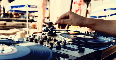DJ's hand close-up and vinyl records on turntables. Summer beach party