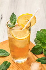 Cold refreshing summer lemonade with ice and lemon slices, decorated with mint leaves in a tall glass