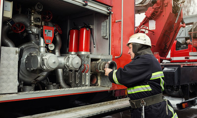 Fireman (firefighter) in action standing  near a firetruck. Emergency safety. Protection, rescue from danger.