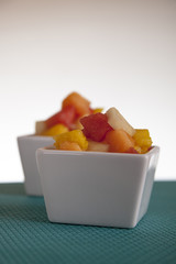 Fruit salad mix of melon, banana, watermelon, orange and pineapple in a small porcelain bowl