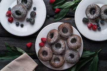 donuts, chocolate, berries, leafs, old wooden table, white plates