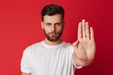 Serious young man showing stop gesture