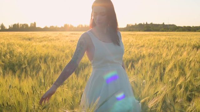 young pregnant tattooed female having fun in field during sunset