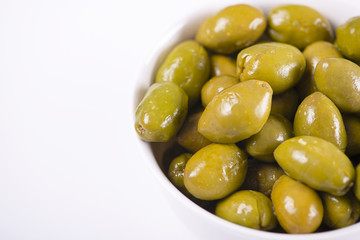 Close-up of olives in a white bowl on white background. Food Copy space.