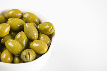 Close-up of olives in a white bowl on white background. Food Copy space.