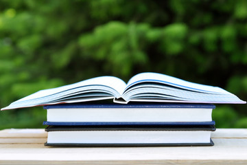 Naklejka premium book with open empty white pages on the table over green nature background outdoor