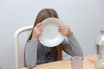 Bambina che mostra un piatto vuoto