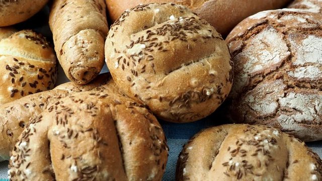 Heap of various bread rolls sprinkled with salt, caraway and sesame. Fresh rustic bread from leavened dough. Assortment of freshly of bakery products