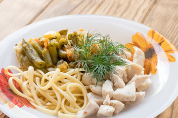 Chicken meat in a plate with fried vegetables and pasta