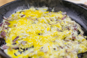 Scrambled eggs with onions in a frying pan.