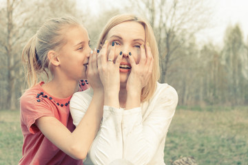 The daughter tells secrets to the mother's ear. Toned.