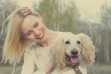A joyful woman with a dog hugs and fools around in nature. Toned.