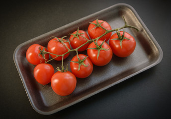 Natural-looking tomatoes on dark background. Selective focus.