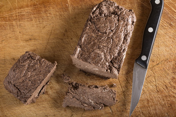 Piece of chocolate halvah over wooden background with kitchen knife