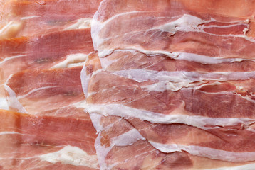 Sliced italian prosciutto background. meat texture closeup. top view