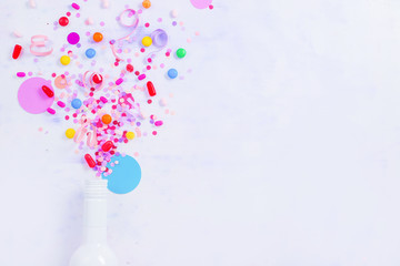 Bottle with bursting confetti flat lay on a white background, party concept with copy space