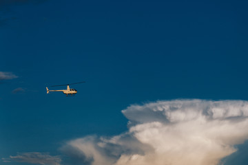 Fototapeta na wymiar Flight, aviation and transport concept. Horizontal shot of white helicopter flies high in blue sky with clouds. Military chopper or airplane in heavens