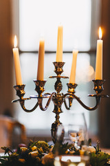 Retro candlestick with five white wax burning candles on served table. Antique style and decoration concept. Calm atmosphere in luxury restaurant. Festive decor.