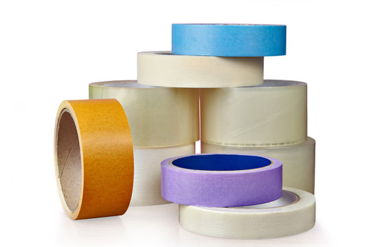 Coils of plastic and paper adhesive tape, on  white.