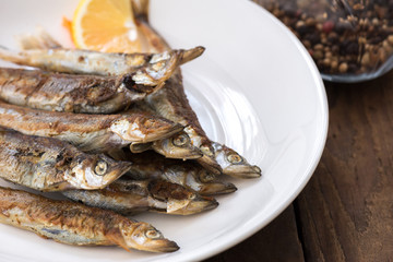 Grilled fish capelin or shishamo on white plate

