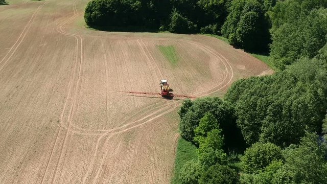 Farm tractor in early spring spraying  crop field, aerial view