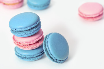 Stack of tasty macaroon biscuits of green and pink color close-up on a white background. French almond cookies. Copy space. Selective focus.