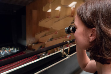 Frau benutzt ein Opernglas in einem Theater