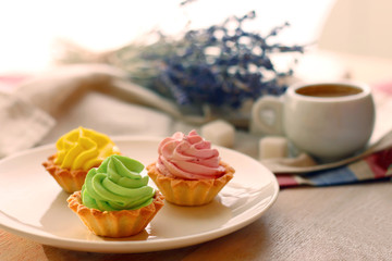 cake basket with cream. three basket on plate and flowers with coffee on back
