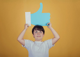 niño con un like grande sobre fondo amarillo