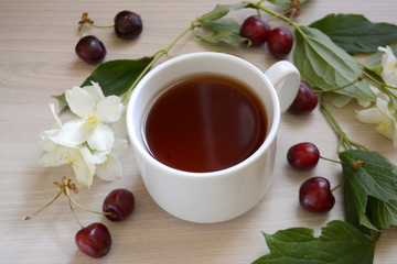 Cup of tea, cherry and flowers on the table