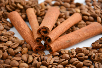 five cinnamon sticks surrounded by coffee beans