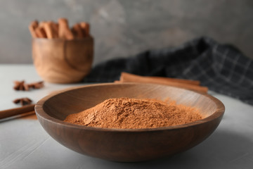 Bowl with aromatic cinnamon powder on table