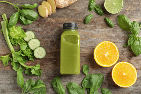 Flat lay composition with bottle of delicious detox juice and ingredients on wooden background