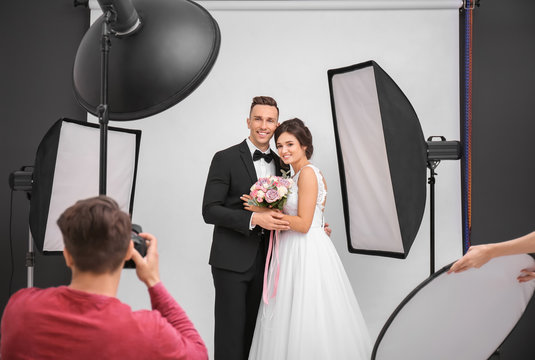 Professional photographer taking photo of wedding couple in studio