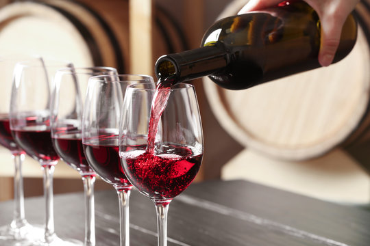 Fototapeta Woman pouring delicious red wine into glass, closeup