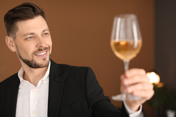 Young man with glass of wine indoors