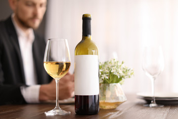 Man with glass of wine at table in restaurant