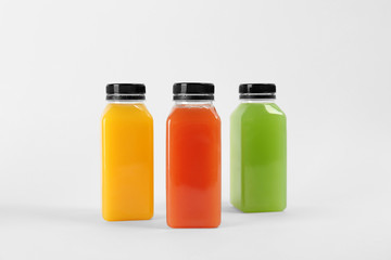 Fototapeta na wymiar Bottles with delicious colorful juices on white background