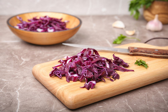 Wooden board with chopped red cabbage on table