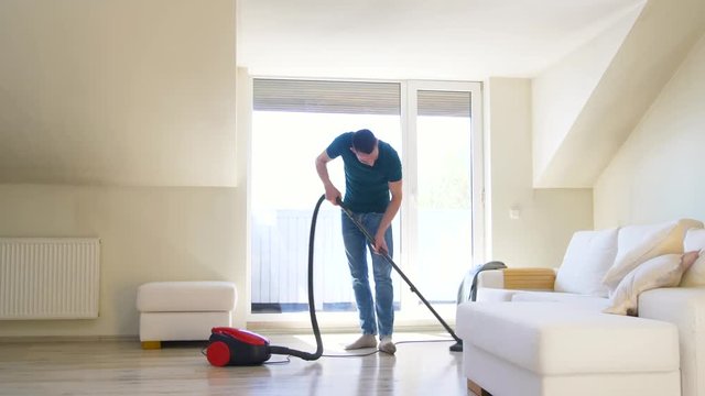 household and cleaning concept - man with vacuum cleaner at home