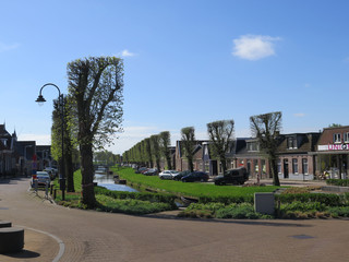 cars parked on green verge above canal in Dutch fishing village